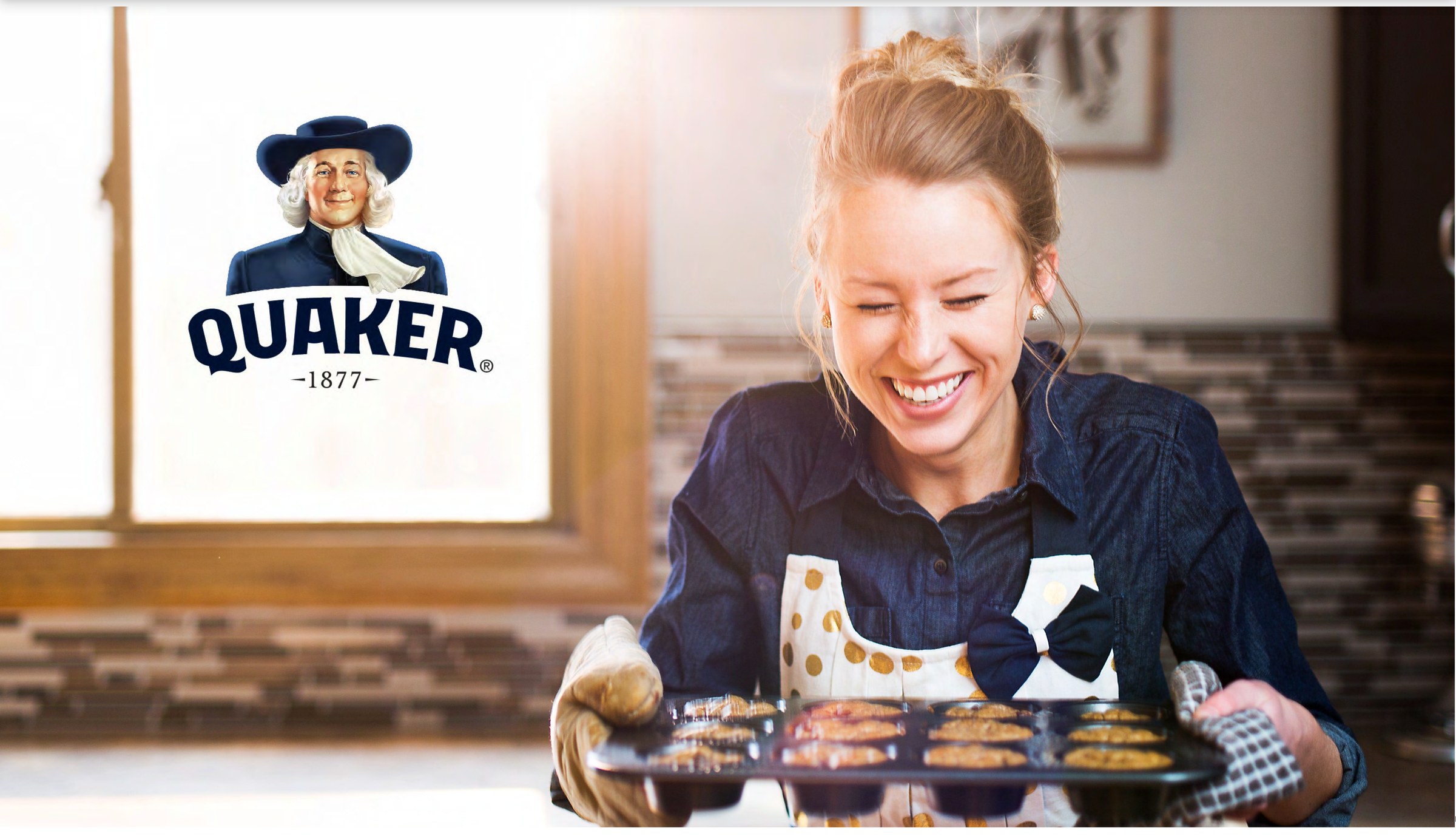 Quaker baking — a baker holding a tray of fresh muffins