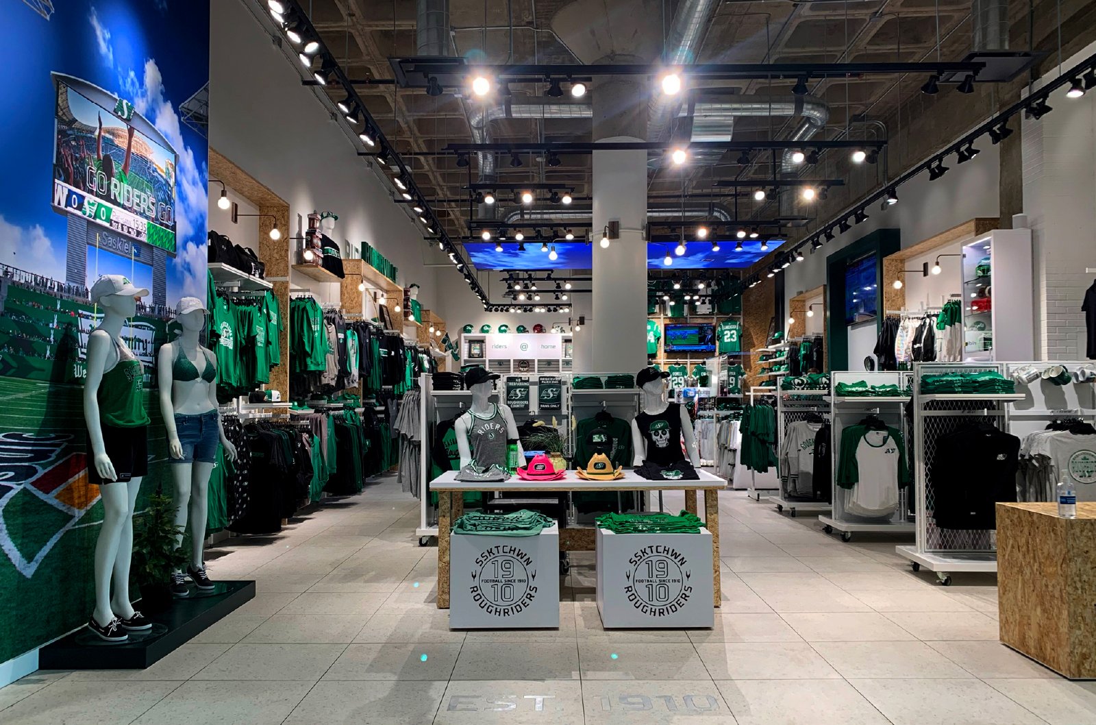 Wide view of the Riderville store — merchandising, sky-ceiling screens and EST. 1910 floor graphic