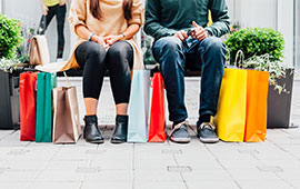 Man and woman sitting on bench shopping bags