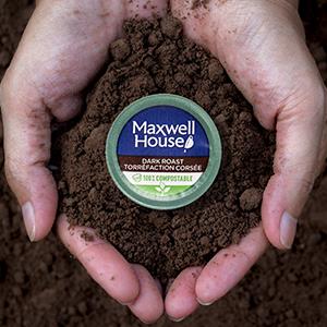 Maxwell house coffee ground in palm of hands with a round package