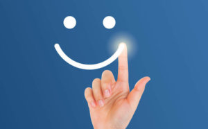 Person drawing smile with finger on a blue background