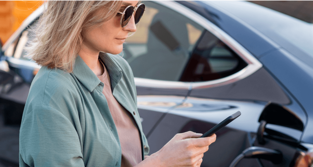 Women texting outside of electric car charging