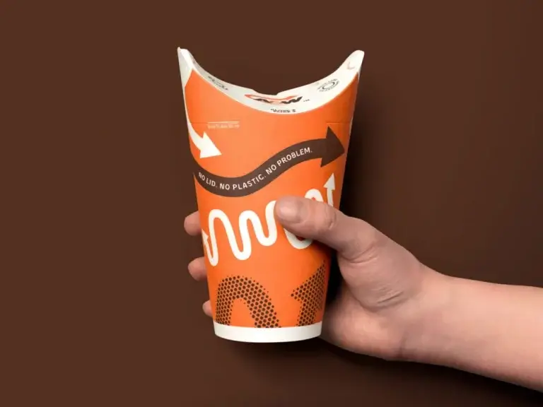 A&W Canada's New zero cup being held on a brown background by a human hand