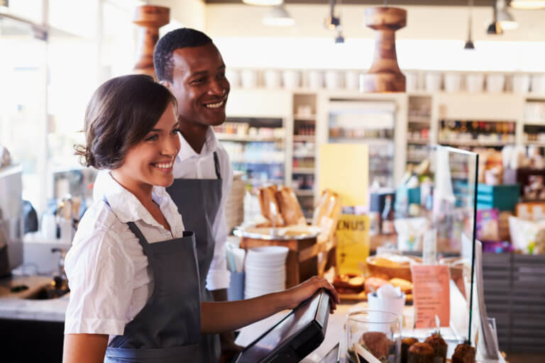 Employees working in a coffee bar behind a service counter smiling